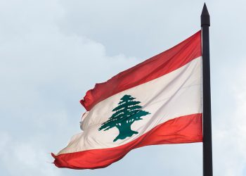 Torn Lebanese flag against an overcast sky