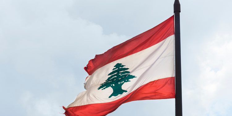 Torn Lebanese flag against an overcast sky