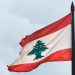 Torn Lebanese flag against an overcast sky