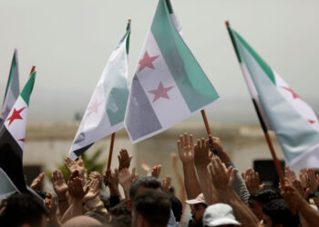 Displaced Syrians hold Free Syrian army flags during a protest calling for an end to the strikes and for Ankara to open the frontier at the Atmeh crossing on the Syrian-Turkish border, in Idlib governorate, Syria May 31, 2019. REUTERS/Khalil Ashawi