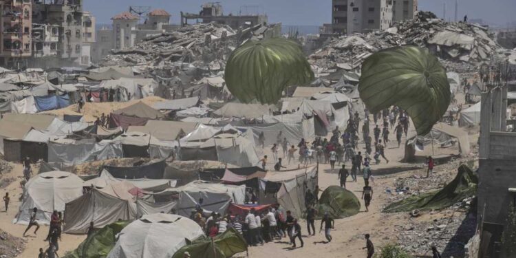 Palestinians rush to collect humanitarian aid airdropped by parachutes into Gaza City, northern Gaza Strip, Thursday, Aug. 7, 2025. (AP Photo/Jehad Alshrafi)