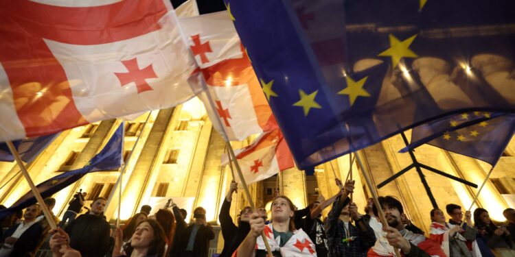 Protesters wave Georgian national and European flags during a demonstration outside the parliament building as they protest against a draft bill on "foreign influence" in Tbilisi on April 17, 2024. Thousands rallied in Georgia on April 17, 2024 after lawmakers advanced a controversial "foreign influence" law that opponents say will undermine Tbilisi's longstanding European aspirations. (Photo by Giorgi ARJEVANIDZE / AFP)